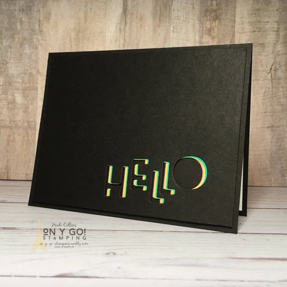 Pops of color peek out from a die-cut sentiment on this black on black hello card. This stunning handmade card will impress anyone and make them smile. Plus, the technique is so easy to do!